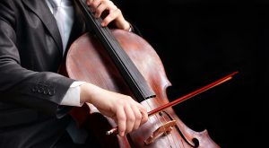 A person playing cello with their hands holding the instrument